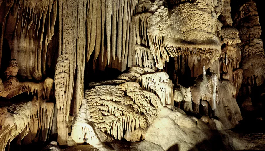 The image showcases an array of stalactites and stalagmites forming intricate natural sculptures in a dimly lit cave.