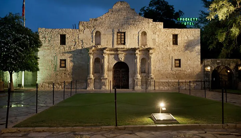 This is a nighttime image of the historic Alamo mission building illuminated by outdoor lighting in San Antonio Texas