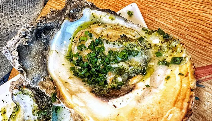 The image shows a large, dressed oyster on the half shell garnished with green onions.