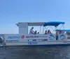 A group of people enjoy a sunny day on a small boat with a blue canopy out on the water