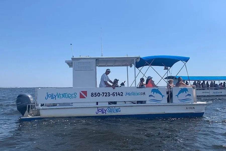 A group of people enjoy a sunny day on a small boat with a blue canopy out on the water.