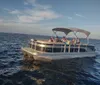 A group of people enjoy a sunny day on a small boat with a blue canopy out on the water