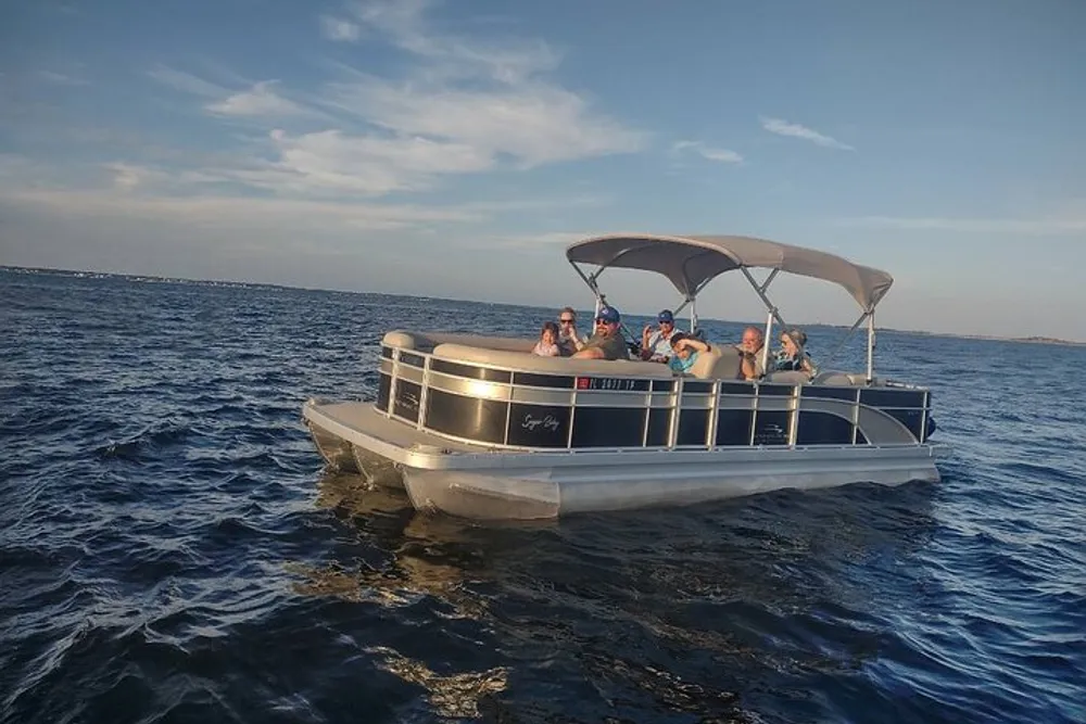 A group of people are enjoying a boat ride on a pontoon boat on the water under a clear sky