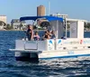 A group of people enjoy a sunny day on a small boat with a blue canopy out on the water