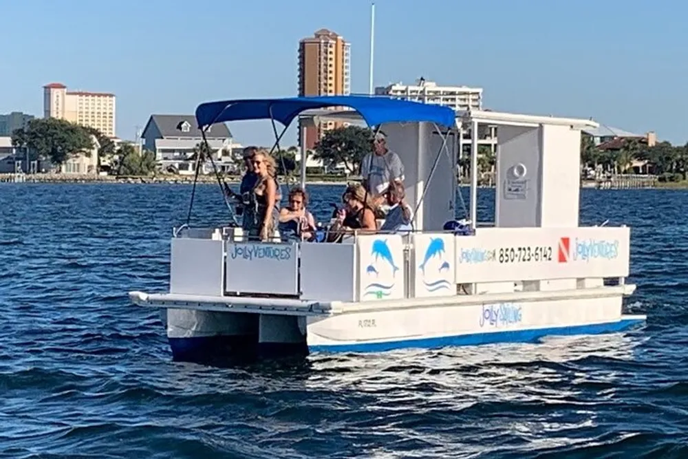 A group of people is enjoying a sunny day on a small pontoon boat on calm waters with buildings visible in the background