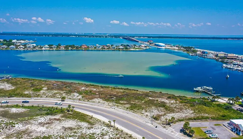 An aerial view of a coastal area showcasing a bridge connecting two land masses with boat marinas and turquoise waters