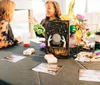 A woman is sitting at a table adorned with mystical and festive decorations possibly engaged in a fortune-telling session with another person whose back is to the camera