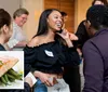 The image shows a group of people engaging in conversation at what appears to be a social event with a smaller inset picture of a salmon dish placed in the corner