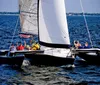 A group of people are enjoying a day of sailing on a multi-hull sailboat on a large body of water