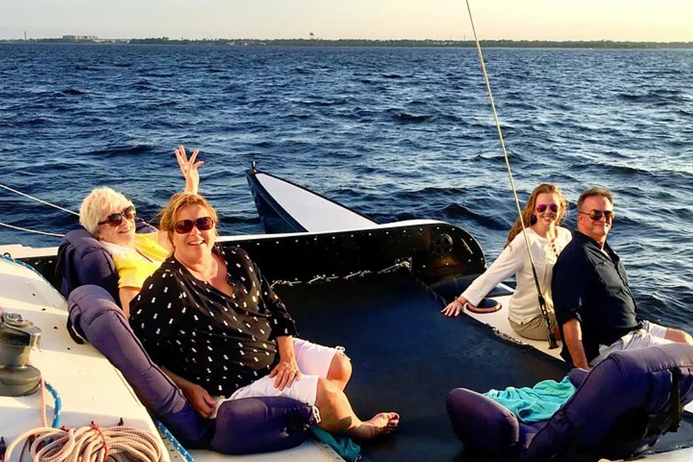 Four people are enjoying a sunny day on a boat with one person playfully giving a peace sign to the camera