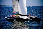 A group of people are sailing on a trimaran, enjoying a sunny day on the water.