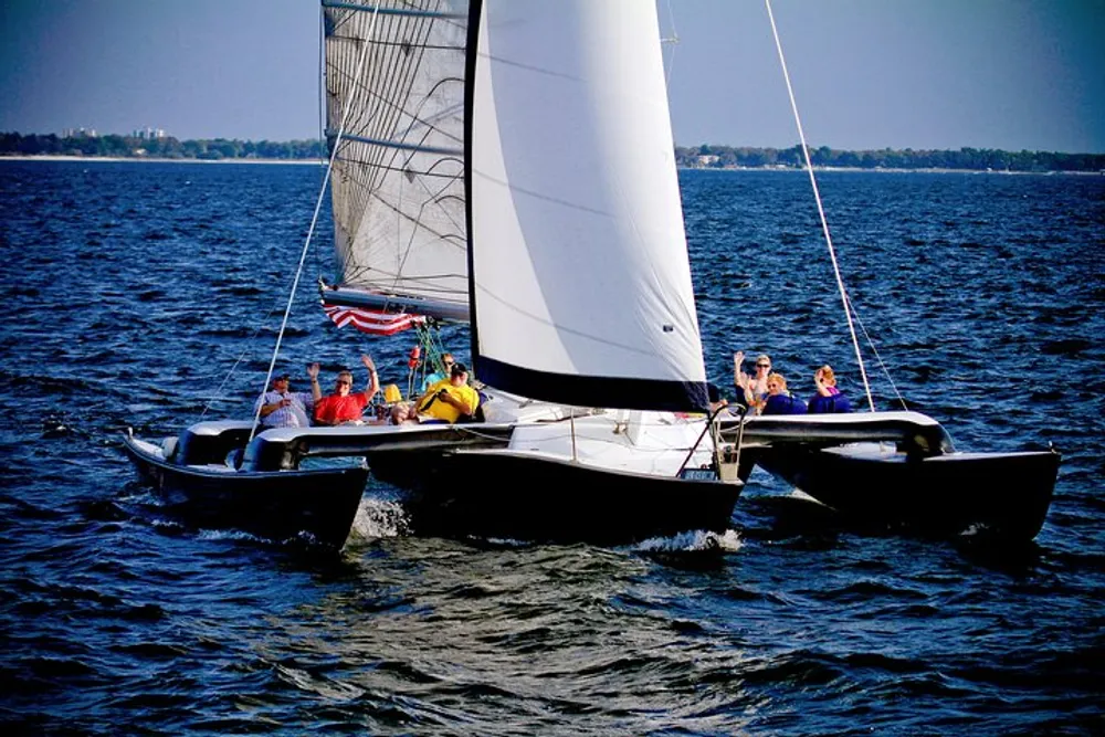 A group of people are sailing on a trimaran enjoying a sunny day on the water