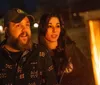 A man and a woman are enjoying a warm moment next to an outdoor fire at night