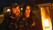 A man and a woman are enjoying a warm moment next to an outdoor fire at night.