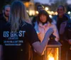 A group of people is listening to a person holding a lantern during what appears to be a ghost tour given the context provided by the text on the back of the shirt