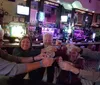 A group of five cheerful people are toasting with shot glasses at a bar with a festive atmosphere