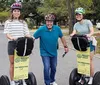 Three people are smiling and standing with Segways on a street likely prepared for a guided tour