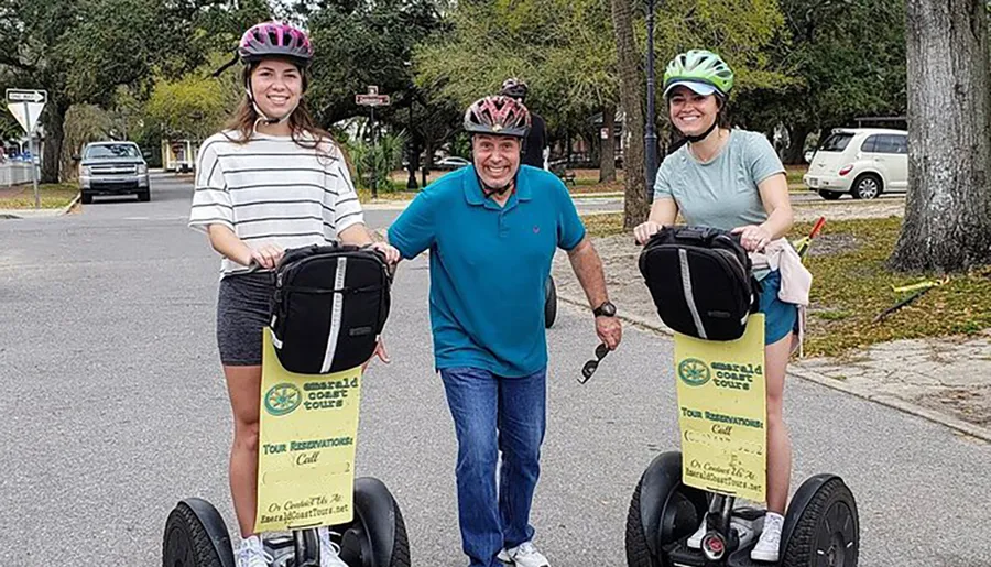 Three people are smiling and standing with Segways on a street, likely prepared for a guided tour.