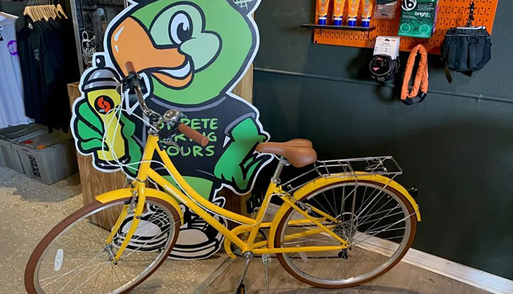 A cutout of an anthropomorphic frog character holding a spray paint can is positioned as if it is riding a real yellow bicycle within a store