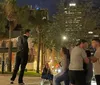 A person is performing a slackline walk in an urban night setting while onlookers watch