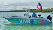 A person is seated on a vibrantly decorated boat flying the American flag on calm waters.
