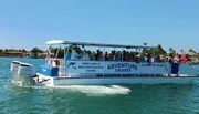 A group of people are enjoying a sunny day on a shelling and dolphin watch tour boat cruising through blue waters.