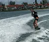 A person is wakeboarding on a body of water with houses in the background