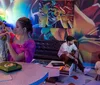 A family enjoys time together in a vibrantly colored room where a young child and a woman play with an old-fashioned telephone and another child and a man interact with a vintage television