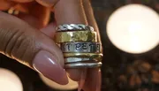 A person is holding a stack of rings with varied designs, including one that says 