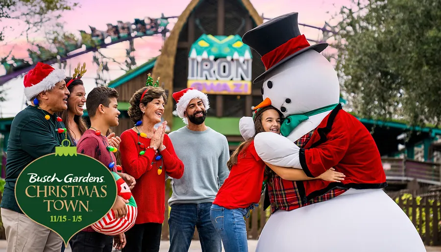 A group of people wearing festive Christmas attire is happily interacting with a person in a snowman costume at Busch Gardens' Christmas Town event.