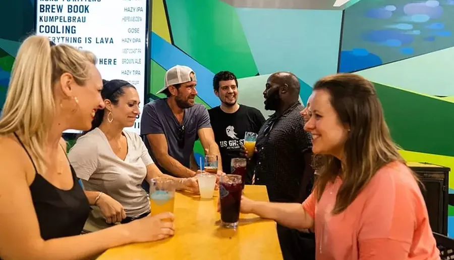 A group of people are enjoying drinks and conversation at a bar with vibrant interior decor.