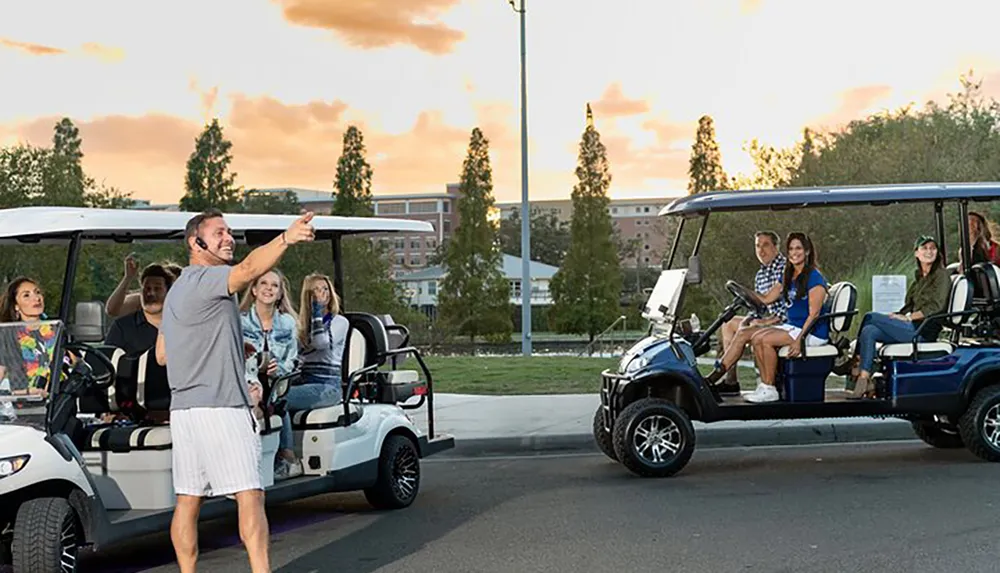 A group of people are riding in golf carts with one man standing gesturing and speaking possibly as a guide or leader during a neighborhood or campus tour at dusk