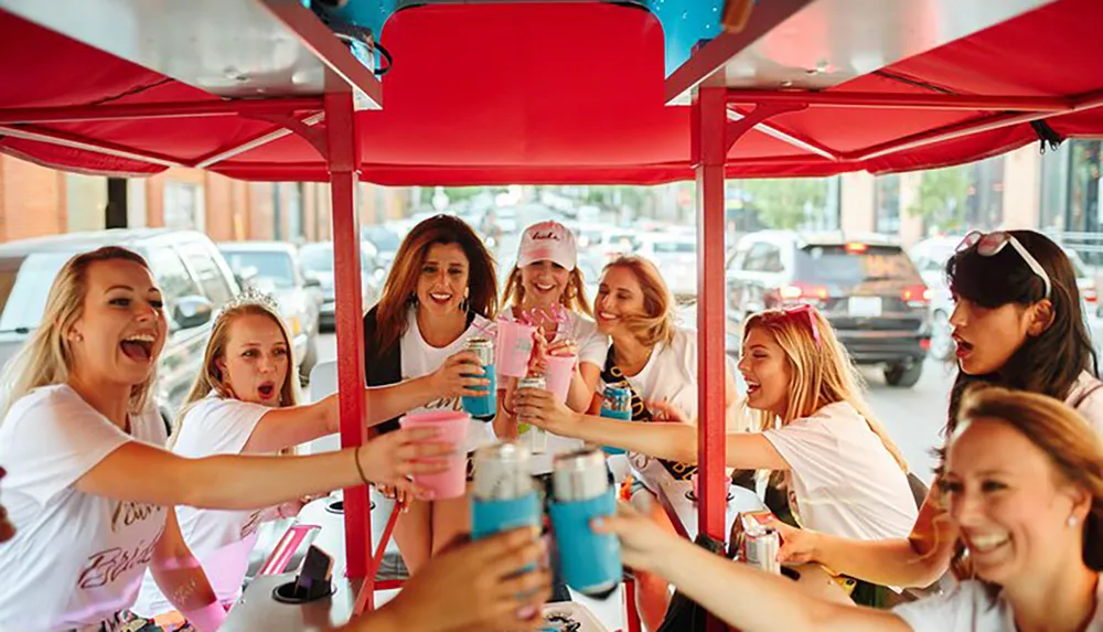 A group of joyful friends are toasting with drinks while enjoying a ride on a pedal pub