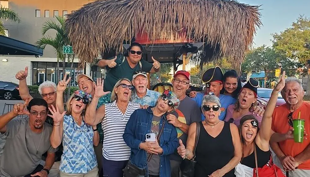 A group of cheerful people are posing for a photo outdoors some wearing pirate hats and making playful gestures