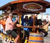 A group of people is joyfully riding a pedal-powered bar on wheels down a street