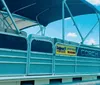 A group of people is enjoying a sunny day on a red pontoon boat at a marina filled with various boats and yachts