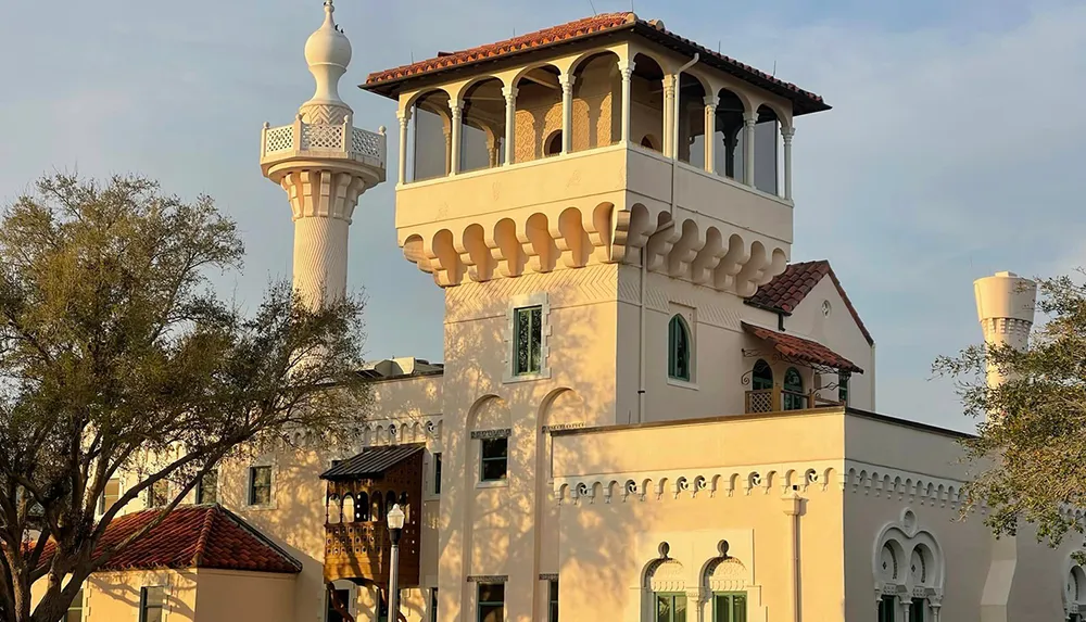 This image features a building with architectural elements reminiscent of Islamic design including a minaret-like tower set against a clear sky