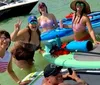 A group of cheerful people are enjoying themselves on paddle boards and in the water near a boat posing for a group photo