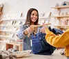 A smiling salesperson is handing a clothing item on a hanger to a customer in a boutique store