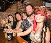 A group of cheerful people is taking a selfie in a bar raising their drinks to the camera