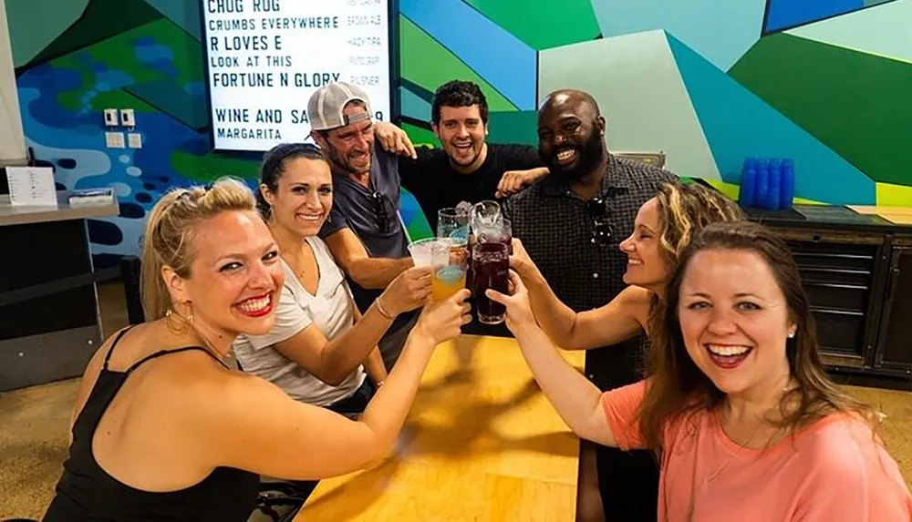 A group of cheerful people is toasting with drinks at a colorful informal gathering or event