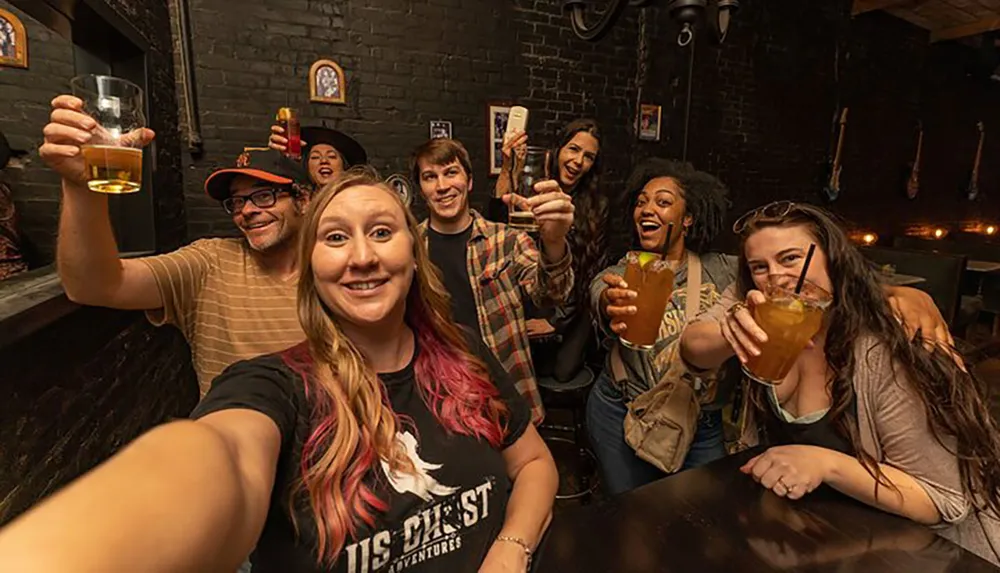 A group of cheerful people is taking a selfie in a bar raising their drinks to the camera