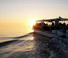 A boat full of passengers is cruising on calm waters at sunset creating a tranquil and beautiful scene