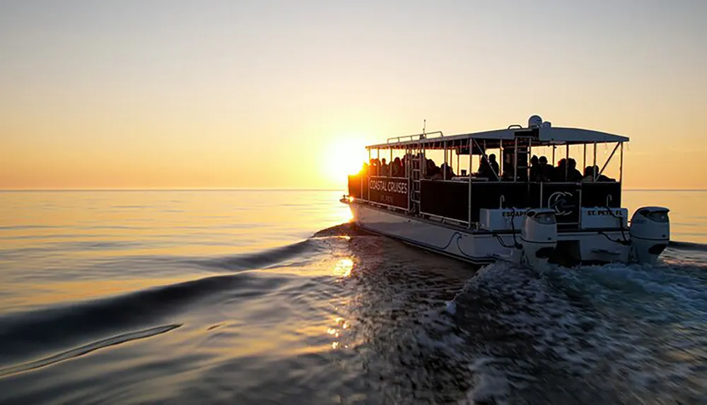 A boat full of passengers is cruising on calm waters at sunset creating a tranquil and beautiful scene