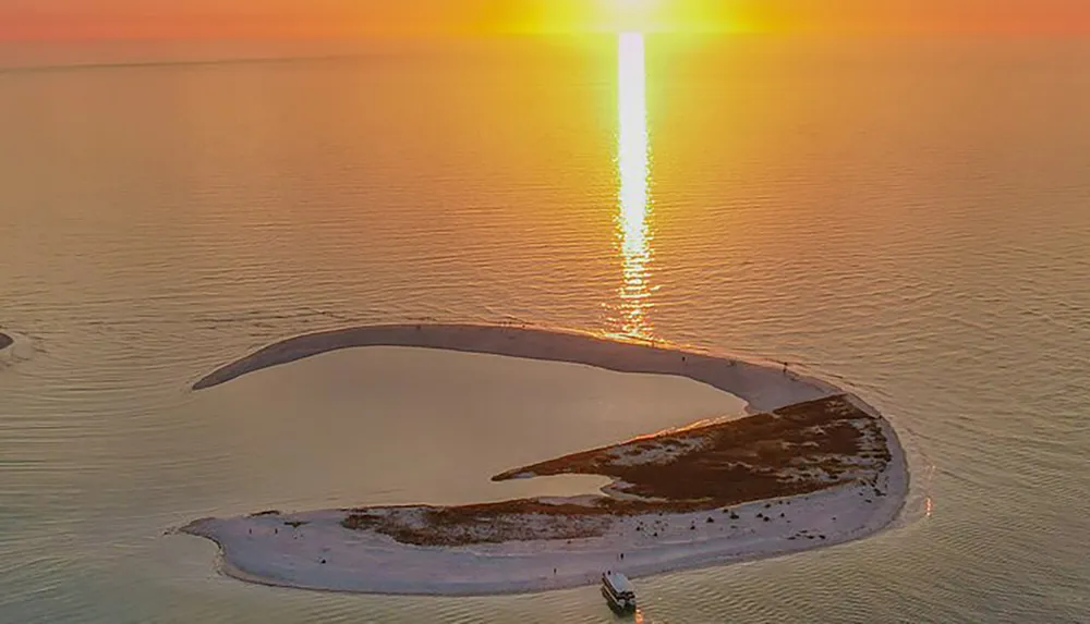 The image captures a serene sunset reflecting over water highlighting a crescent-shaped shoreline that seems to cradle the suns reflection