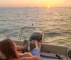 Two people are enjoying a sunset from the back of a boat on the water