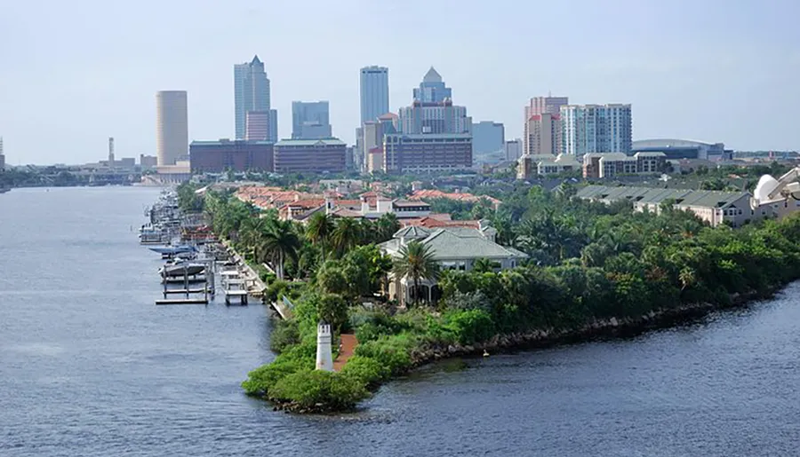The image shows a waterfront view of a city skyline with modern buildings towering over a residential area with docks and a small lighthouse.