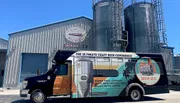 A colorfully wrapped Brew Bus is parked outside the Cigar City Brewing facility, advertising brewery tours and various private events.