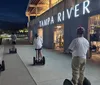 Three people are standing on Segways in front of a large striped sign that spells out TOYS with each person positioned inside one of the letters