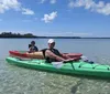 Two people are enjoying kayaking on clear calm water with a beautiful sky overhead